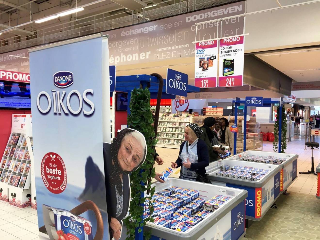 Large format print displays full color printed frontlit Danone rollup for Oikos yoghurt in combination with a full color printed Greek grandmother in forex X-Treme Creations