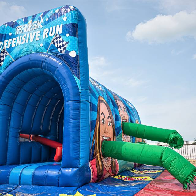 Giant inflatable games Opblaasbare op maat gemaakte Frisk Defensive Tunnel voor merkactivatiedoeleinden met horizontale dynamische buizen als onderdeel van het circuit tijdens het Ostend Beach Festival ontworpen door klant Plug 'n Play X-Treme Creations