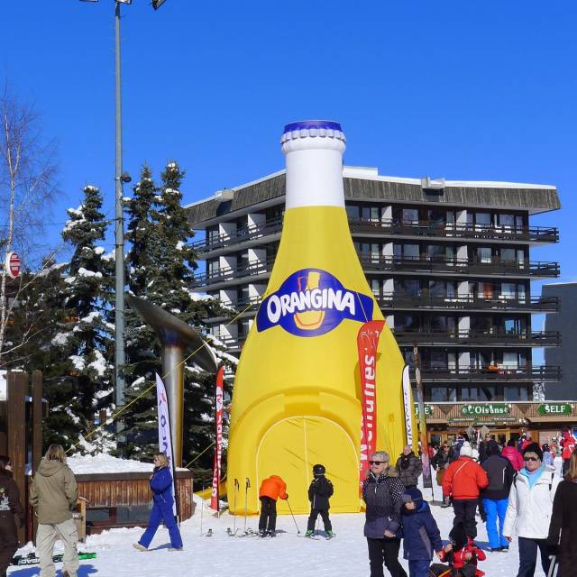 Giant inflatable standen opblaasbare stand in de vorm van een gigantische fles Orangina in de sneeuw van de Franse Alpen X-Treme Creations