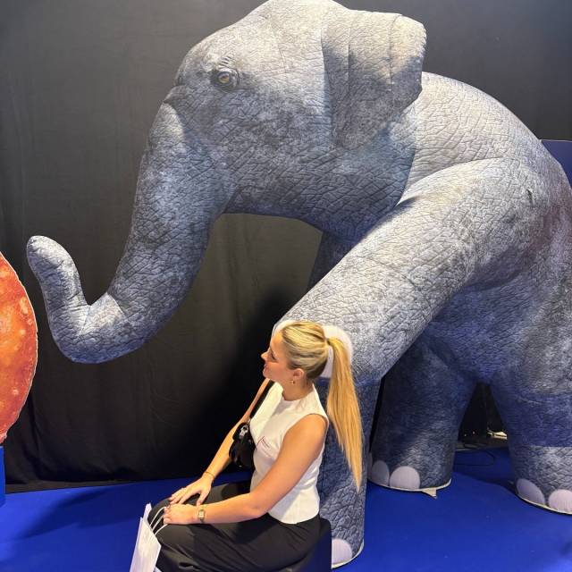 Big inflatable animals inflatable young baby elephant putting his front leg gently on the shoulder of a hostess of the agency Brandactivators X-Treme Creations