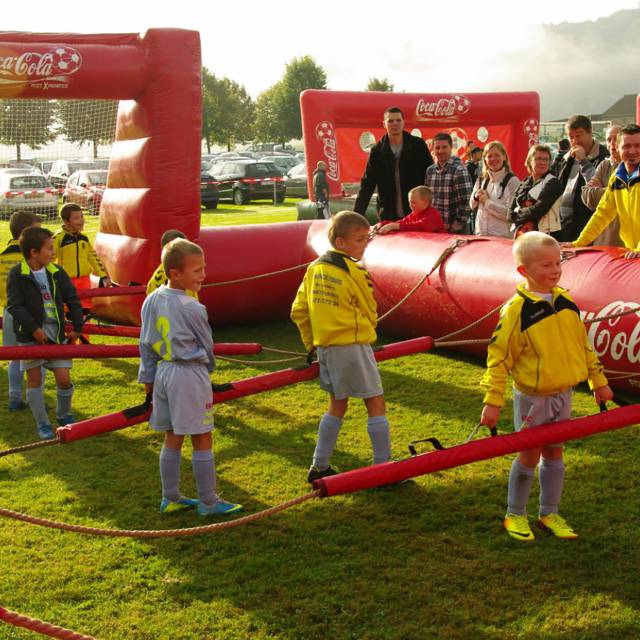 Riesige aufblasbare Spiele Aufblasbarer Fußball boarding von Coca-Cola mit spielenden Kindern als Fußballanimation, die wir menschlicher Tischfußball nennen X-Treme Creations