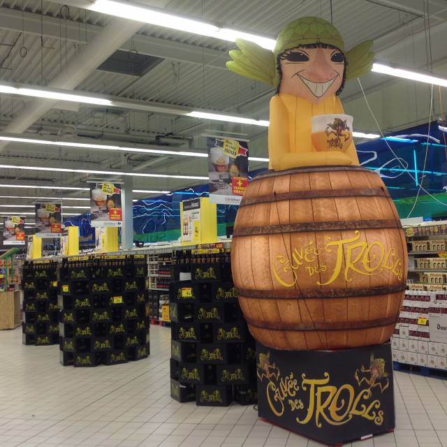 Giant inflatable mascottes et personages personnage gonflable trol sortant d'une caisse éclairée de l'intérieur remplie de bière Troll comme point de vente visible dans un supermarché pour la brasserie Dubuisson X-Treme Creations