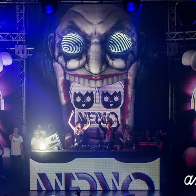 X-Treme Creations 2 female DJ's with hands in the air on stage with inflatable Jester on background with inscription 