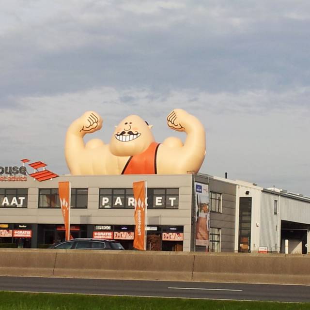 Mascottes et personnages gonflables géants torse d'haltérophile gonflable de 13 m de large sur l'un des 4 toits de FloorHouse le long de l'autoroute A12 à Aartselaar X-Treme Creations