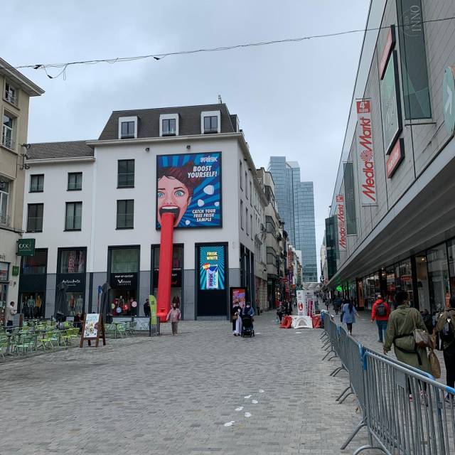 Combinez impression et matériel gonflable combinaison d'un toboggan en forme de langue gonflable comme action d'échantillonnage pour la marque Frisk avec une banderolle en full quadri contre la façade dans la rue Neuve à Bruxelles X-Treme Creations