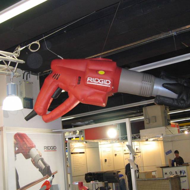 Giant inflatable product enlargements inflatable metal pipe cutting tool 3 m long hanging above the Ridgid company booth during a fair X-Treme Creations