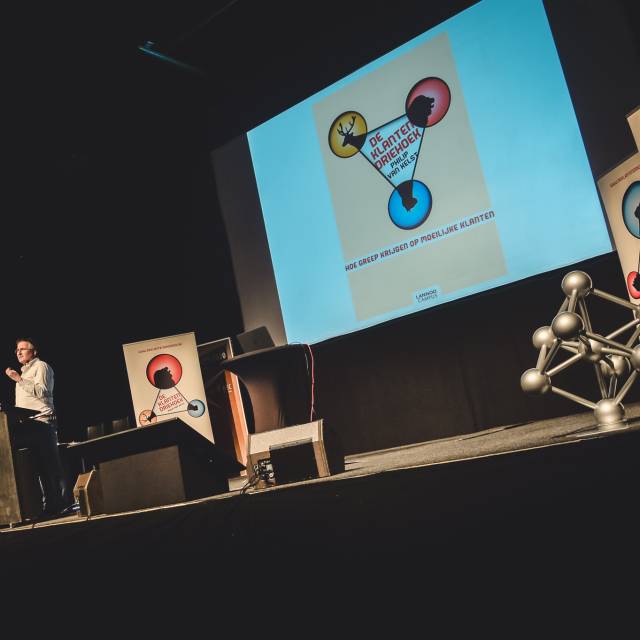 Large format print displays roll-up on Lannoo Campus stage during a presentation of a book about difficult customers X-Treme Creations