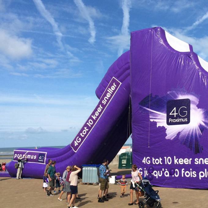 Large inflatable promotional material | X-Treme Creations Purple inflatable slide on the beach with the slogan: 4G to 10 times faster and the Proximus logo. Events  & Corporate branding  & Brand activation  &  Proximus Demonstr8 X-Treme Creations