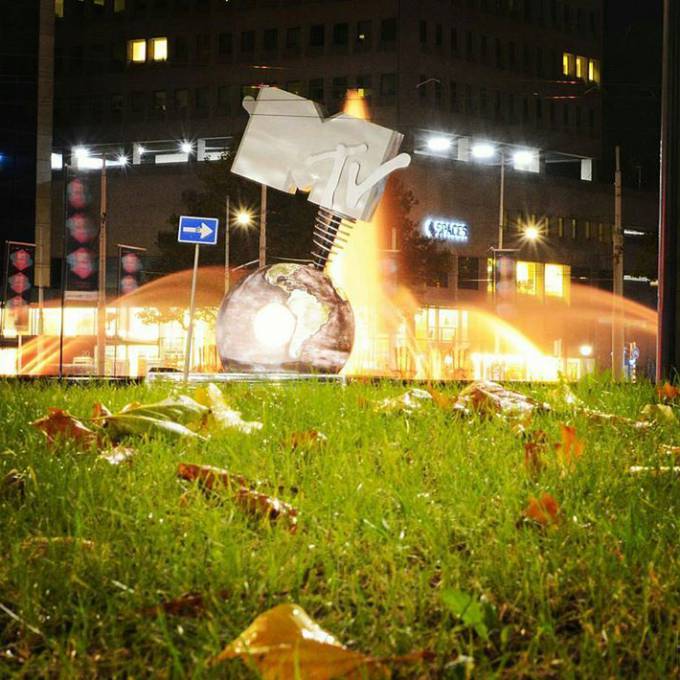 Gonflables géants comme matériel de promotion | X-Treme Creations Vue de dessous du MTV Globe avec de l'herbe au premier plan et des feuilles mortes devant la fontaine la nuit Events  & La renommée de la marque  &  VKN Projecten X-Treme Creations